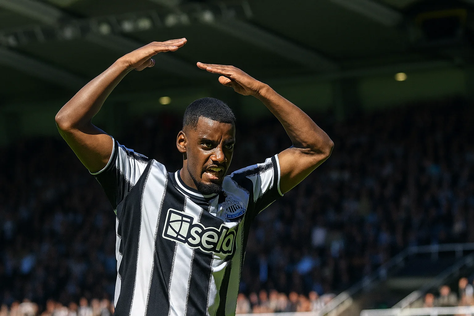 Alexander Isak célébrant un but avec Newcastle, levant les bras au-dessus de la tête devant les supporters.