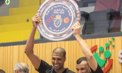 Joueurs du FUS Rabat célébrant leur titre de champion du Maroc 2024-2025 en basketball, brandissant le trophée dans une ambiance festive.