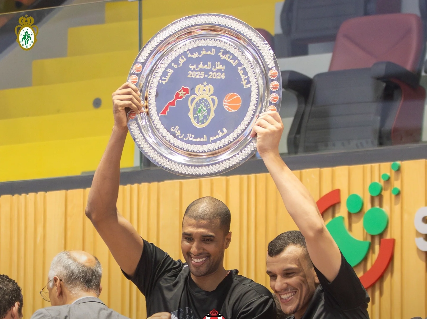 Joueurs du FUS Rabat célébrant leur titre de champion du Maroc 2024-2025 en basketball, brandissant le trophée dans une ambiance festive.