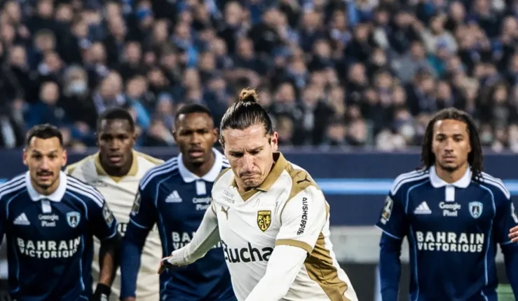 alt="Un joueur de Lens tire un penalty contre le Paris FC lors d’un match de Ligue 1"