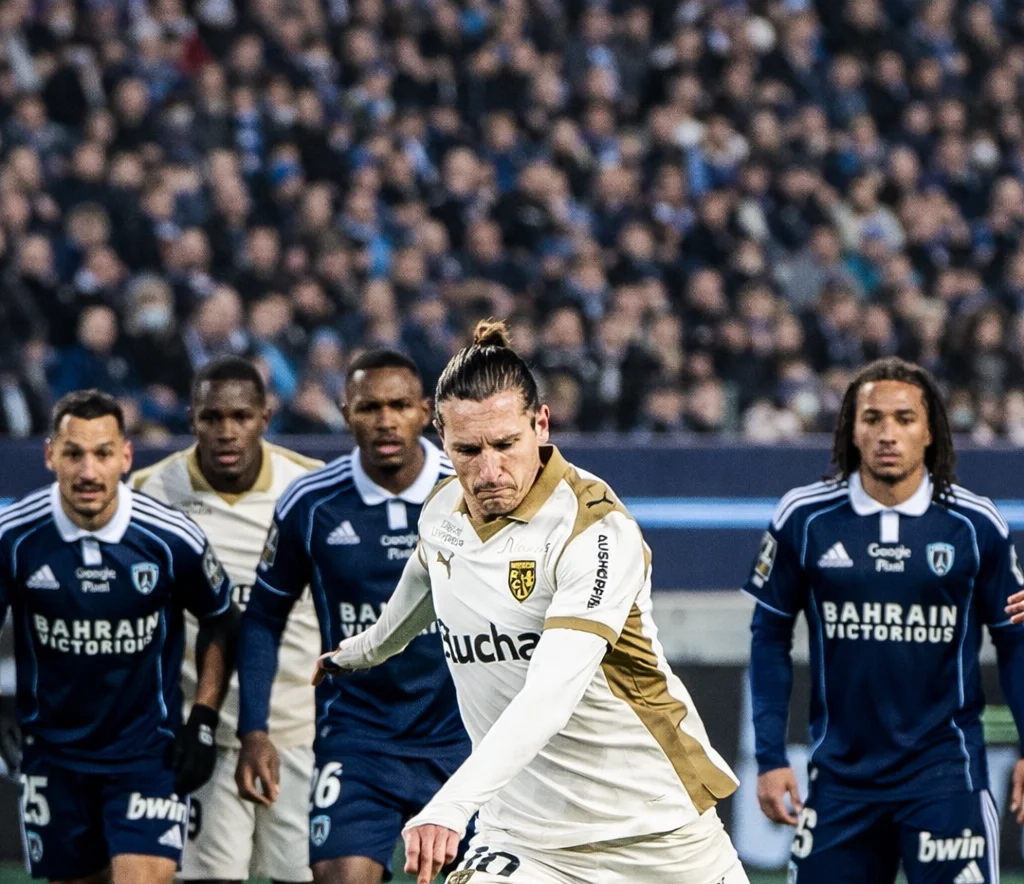 alt="Un joueur de Lens tire un penalty contre le Paris FC lors d’un match de Ligue 1"